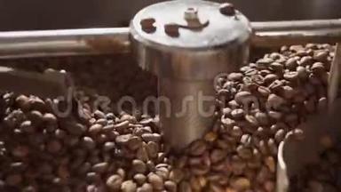 新鲜烤咖啡豆从一个大咖啡烘焙机。 在烘焙设备上烤咖啡豆。 咖啡豆